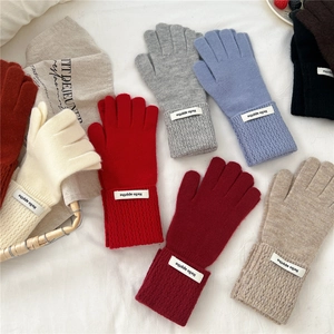Gants d'hiver en tricot épais colorés avec poignets côtelés disposés sur tissu blanc