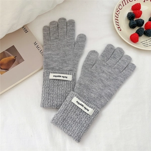 Détail de gants d'hiver en tricot gris épais avec étiquette tissée Hello blanche