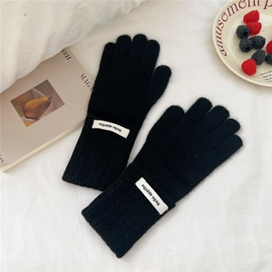 Détail de gants en tricot noirs avec poignets côtelés et étiquette décorative minimaliste