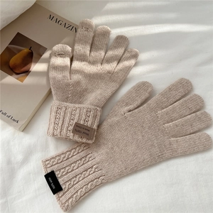 Close-up of beige wool knit gloves with touch-screen fingertip openings on white linen