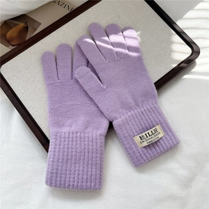 Dettaglio guanti invernali in maglia viola con trama di lana spessa e polsini a coste