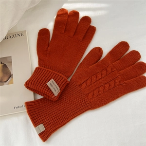 Close-up of cable knit texture on burnt orange 100% wool gloves with ribbed cuffs