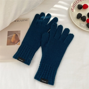 Detail view of dark teal wool knit gloves with braided cuffs and woven composition label