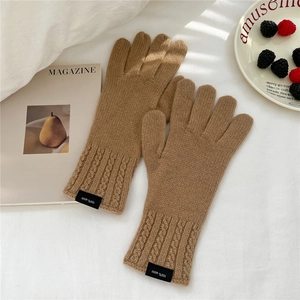 Detail of wool knit gloves featuring 100% wool label and cozy cable knit texture