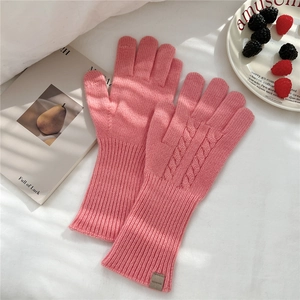 Detailed close-up of pink 100% wool knitted gloves with cable knit pattern and long cuffs