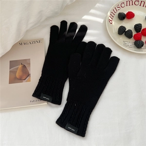 Detail of black wool knit gloves with ribbed cuffs and authentic product label