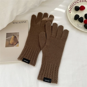 Close-up of brown 100% wool knitted gloves with cable knit cuff and logo label