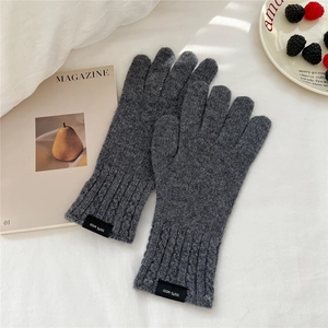 Detail of wool knit gloves showing 100% Wool label and chunky cable knit texture