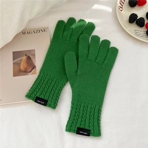 Detailed knit texture of vibrant green 100% wool gloves with 100% wool label detail