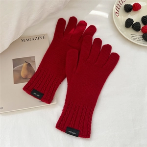 Detailed macro view of red wool knit gloves showing fine texture and 100% wool label