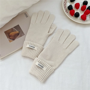 Detail of cream knitted wool gloves with open thumb for touch screen and wool label