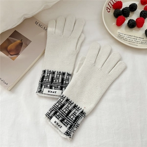 Détail de gants en tricot crème avec texture tissée et étiquette ZPKR sur tissu blanc