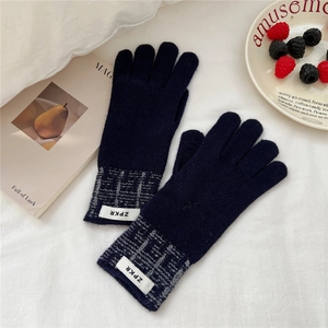 Détail de gants en tricot bleu marine avec poignets à carreaux gris sur un fond chaleureux