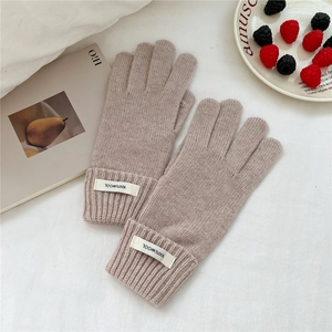 Detail of wool knit gloves featuring ribbed cuffs and white fabric material label