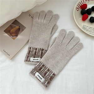 Détail de gants en tricot beige avec motif géométrique et étiquette tissée douce