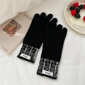 Gros plan de gants en tricot noir avec poignets à carreaux noirs et blancs et étiquette
