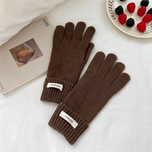 Close-up of brown wool knit gloves featuring a 100% wool label and elastic ribbed cuffs