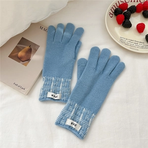 Détail de gants en tricot bleu avec motif à carreaux au poignet et étiquette tissée