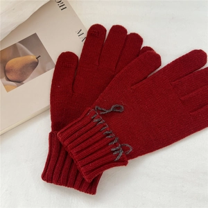 Detail of dark red knit gloves featuring thick texture and ribbed wrist cuffs for warmth