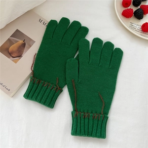 Detail of green thick knitted gloves with ribbed cuffs and brown hand-stitched embroidery