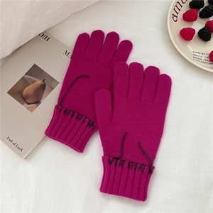 Detailed view of magenta knitted gloves with black embroidery and ribbed cuffs