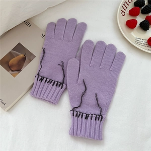 Detailed view of purple knit gloves with black decorative stitching on a white background