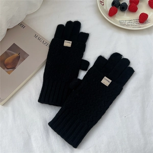 Detail of black knit winter gloves with diamond pattern and cozy ribbed cuffs on fabric