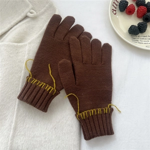 Detail of dark brown knitted gloves with yellow hand-stitched cuffs for winter warmth