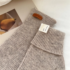 Détail de gants en tricot 100% laine avec étiquette en cuir et texture douce et chaude