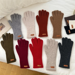 Gants en maille côtelée colorés de style automnal sur une parure de lit blanche