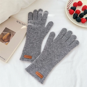 Texture de tricot détaillée de gants d'hiver gris avec détail d'étiquette en cuir brun