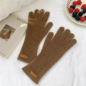 Gros plan de gants en tricot marron avec texture côtelée et étiquette de marque en cuir