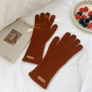 Détail de gants en tricot caramel avec design à deux doigts et étiquette décorative