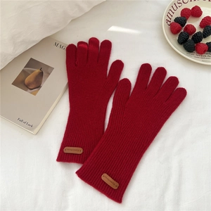 Gros plan de gants en tricot rouge avec rayures texturées et étiquette de marque en cuir
