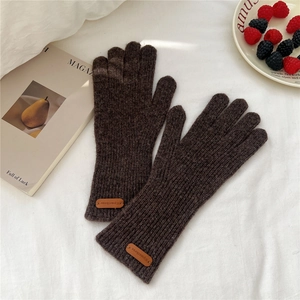 Détail de gants en tricot marron foncé avec texture côtelée et étiquette en cuir
