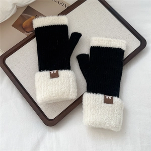 Dettaglio dei guanti in maglia con bordo in peluche bianco e trama a coste nere invernali