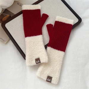Dettaglio di guanti senza dita in maglia rossa con ecopelliccia bianca e patch in pelle