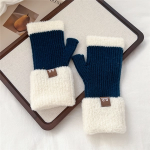 Dettaglio di guanti in maglia blu scuro con bordo in pelliccia e etichetta in pelle