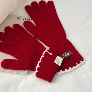 Detail of red wool knit gloves featuring white lace trim and AUVD handmade label