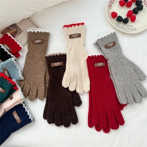 Women's knit gloves with scalloped cuffs and leather tag on a cozy magazine background