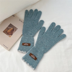 Close-up of blue knit gloves with lace cuffs and brown leather handmade label detail