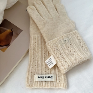 Detailed view of cream knitted gloves showing the fabric care label and ribbed texture details
