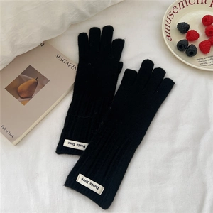 Detailed knit texture of black vertical striped gloves with a woven brand tag on wrist