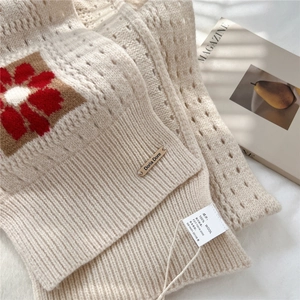 Detail showing the 100% wool material label and intricate knit texture of the flower scarf