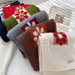 Detail of soft knit wool scarf with colorful floral patterns and hollow stitch texture