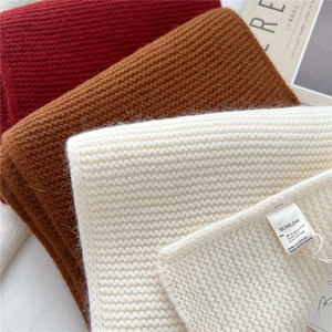 Close-up of wool knit scarves in red, brown, and beige showing soft fiber texture