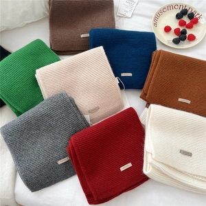 Detailed view of colorful thick knit wool scarves with premium brand metal tag accents