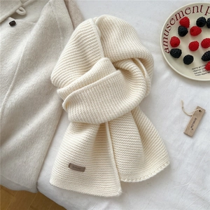 Close-up of cream chunky knit wool scarf with premium brown leather brand logo label