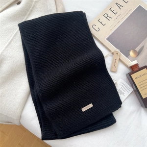 Close-up of black knitted wool scarf with BOWLOW brand label and thick woven texture