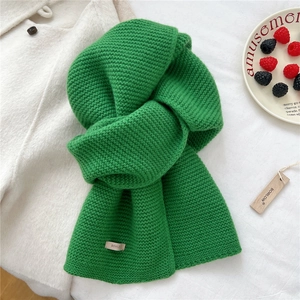 Detailed macro view of grass green thick knit wool scarf with a woven brand logo label